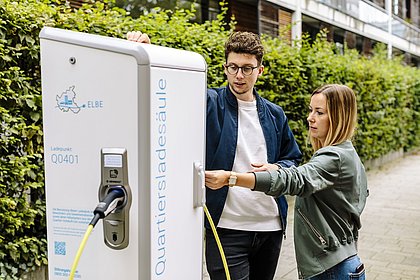 Ein Mann und eine Frau stehen an einer Ladesäule