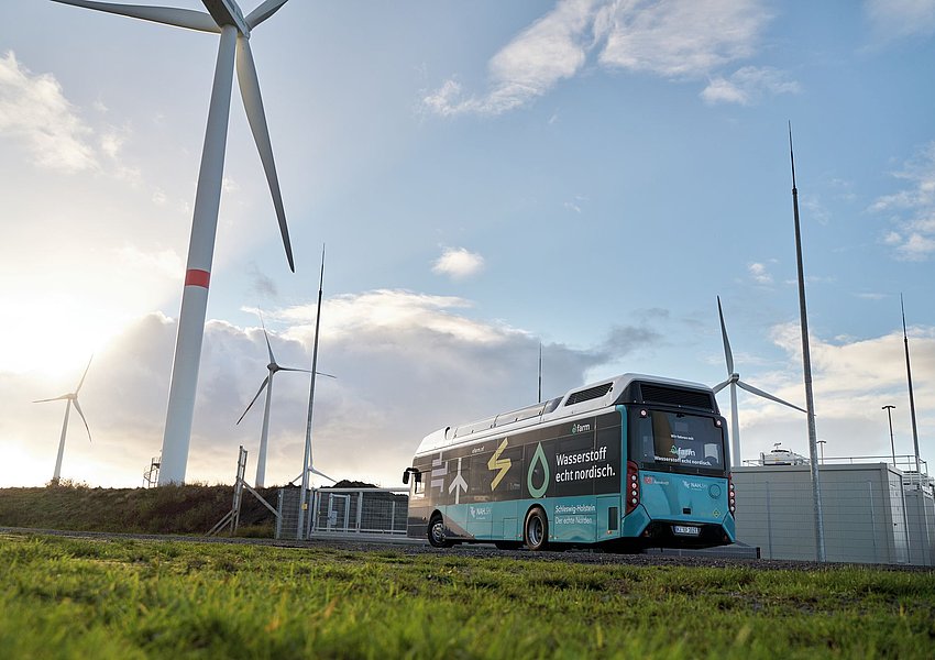 Ein Wasserstoffbus vor Windrädern