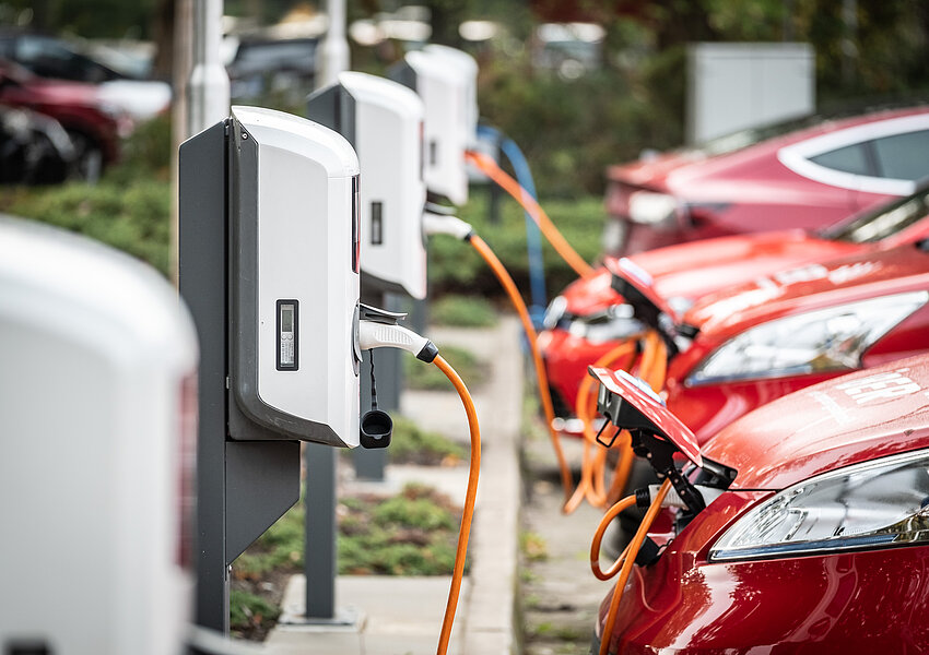 Eine Reihe roter Autos an Ladessäulen