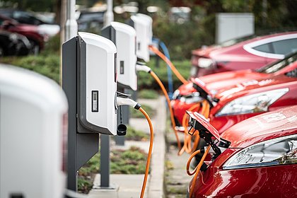 Eine Reihe roter Autos an Ladessäulen
